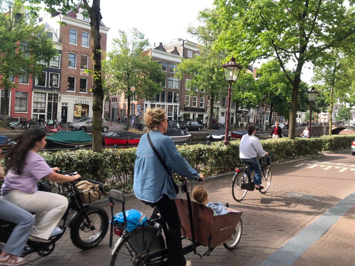 Amsterdam lady on a cargo bike, with other cyclists next to a canal