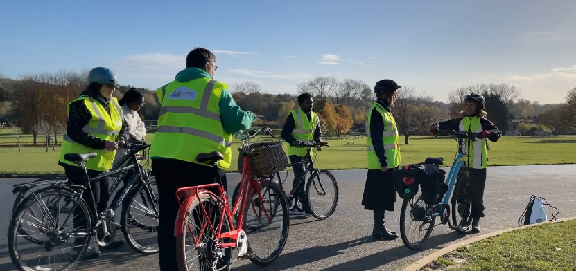 group of adults with bikes in park during cycle lesson