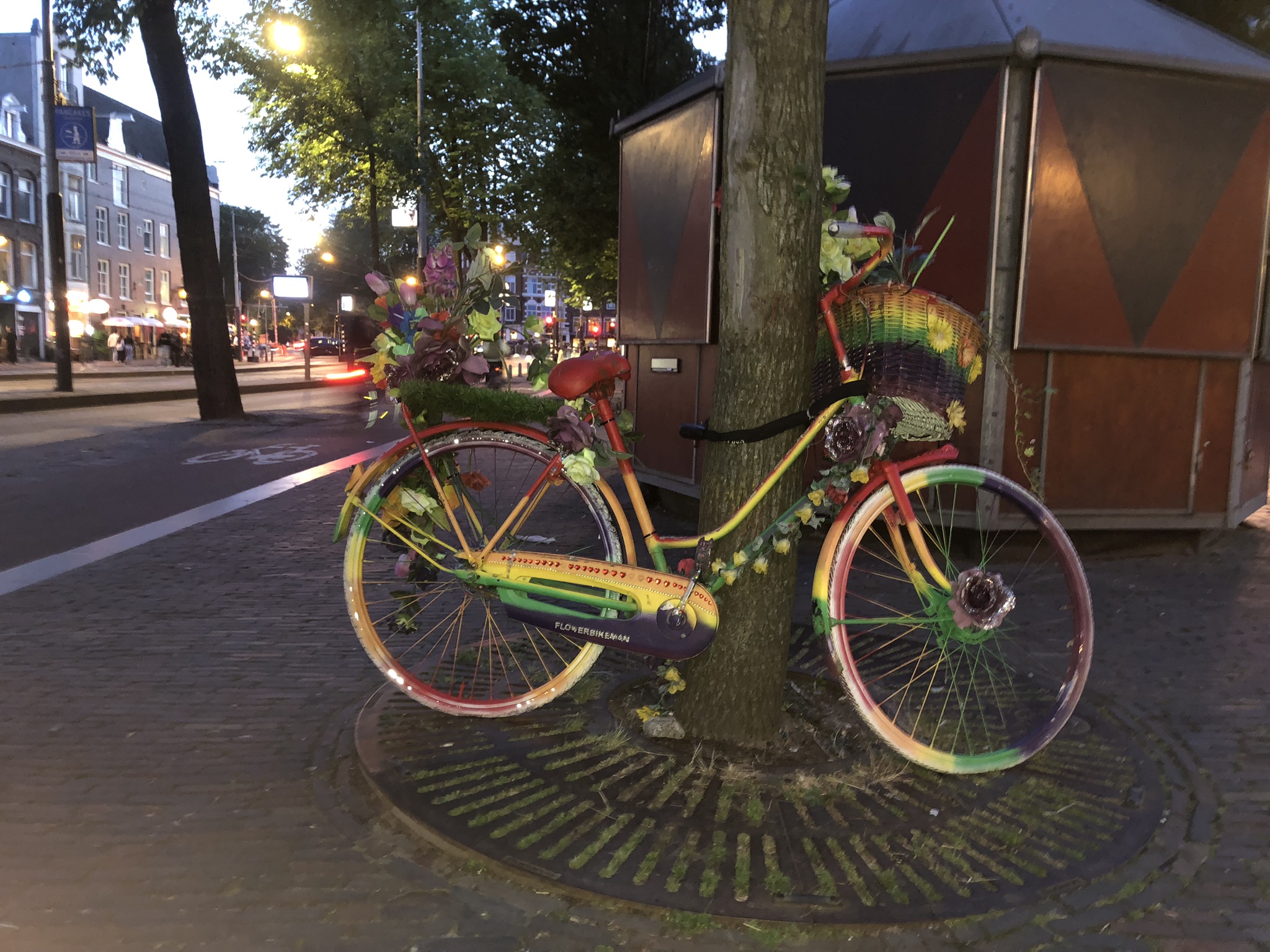 Rainbow painted display bike decorated with artificial flowers.