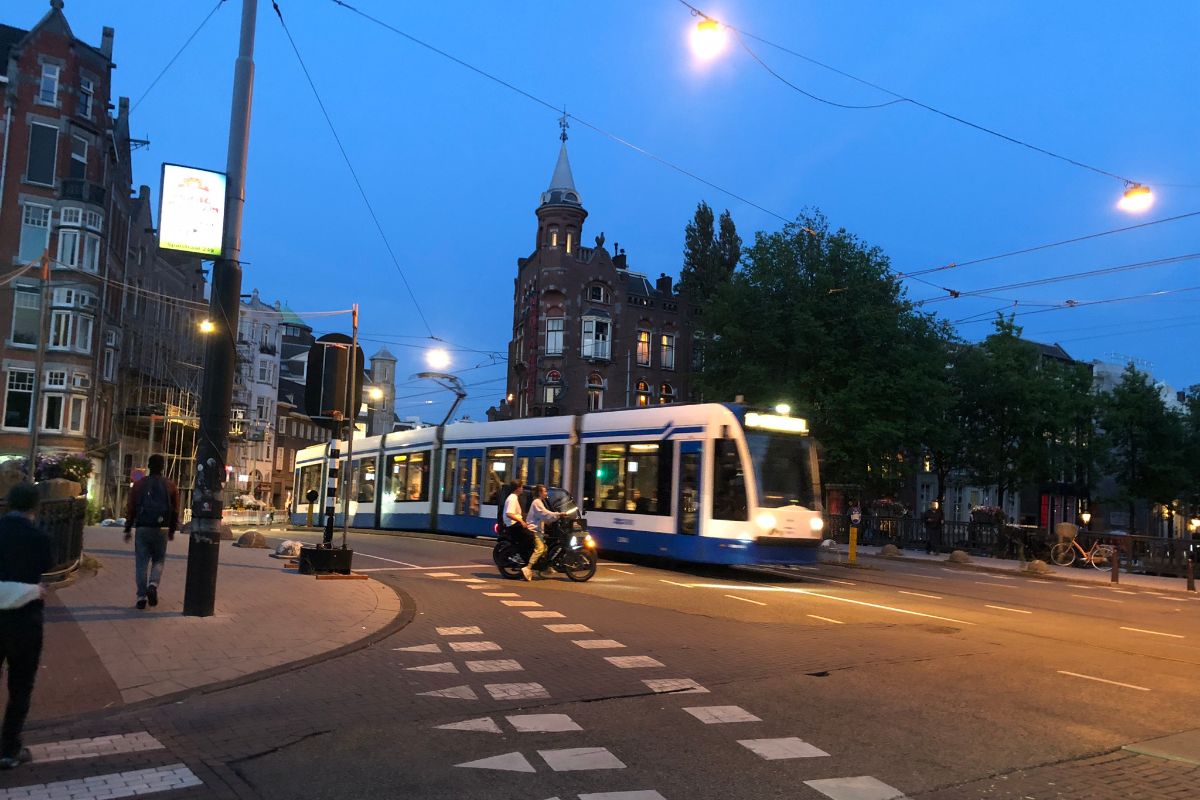 Tram at night with cyclist and pedestrians in view