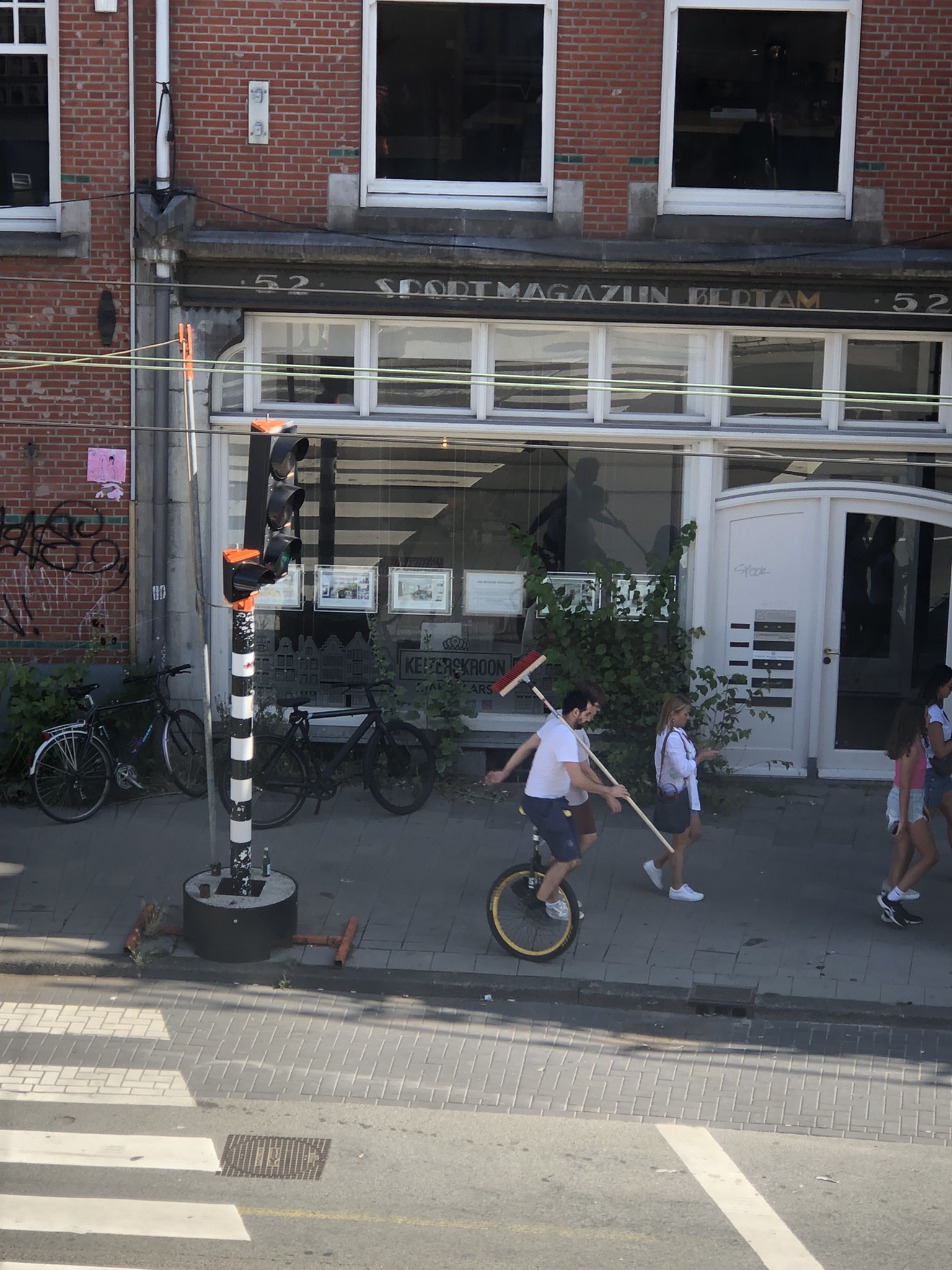 Man riding unicycle and carrying broom in Amsterdam 